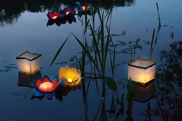 Water burning yellow lanterns on the lake amid tall grass