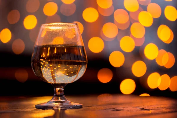 Ποτήρι κρασί σε ένα τραπέζι στο βάθος του ένα κίτρινο bokeh — Φωτογραφία Αρχείου