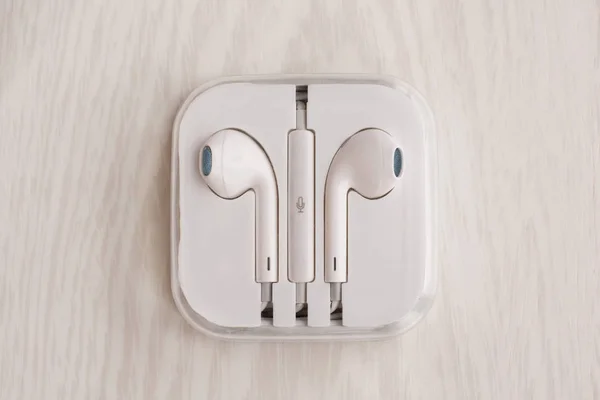 Bir beyaz tahta masanın üstüne yığılmış bir kutu içinde Iphone için kulaklıklar