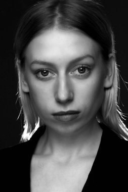 Siyah arka planda siyah takım elbiseli, uzun saçlı, siyah beyaz. İş kadını