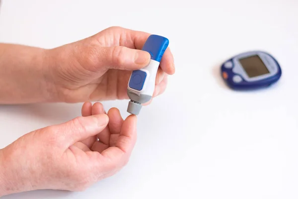 Diabetes gör blod glukos mätning. Kvinna med hjälp av lancet och Glukometer. Stockfoto