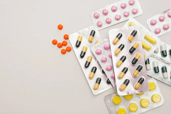 Billigt av medicinska piller i gula, rosa och gröna färger. Piller i plastförpackningar. Stockbild