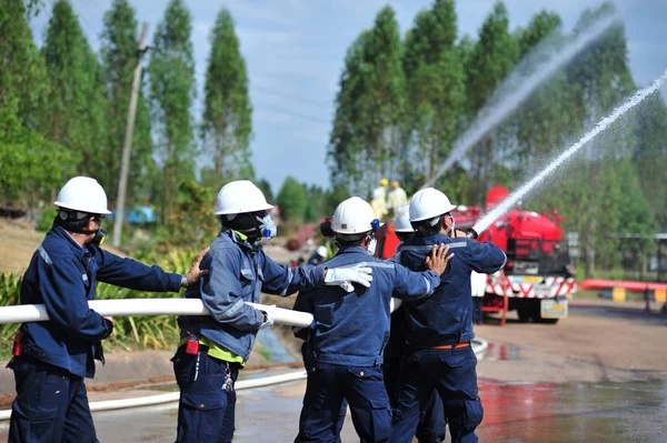 Группа пожарных человек вводят спрей воды в огонь acc — стоковое фото