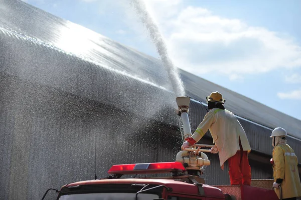 Gruppe von Feuerwehrmännern spritzt das Löschwasser — Stockfoto