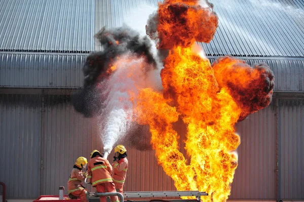 男を注入、消防士のグループが acc を火に水をスプレーします。 — ストック写真
