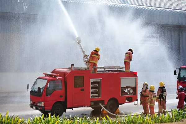 Ομάδα των πυροσβεστών άνθρωπος είναι ένεση σπρέι το νερό στη φωτιά acc — Φωτογραφία Αρχείου