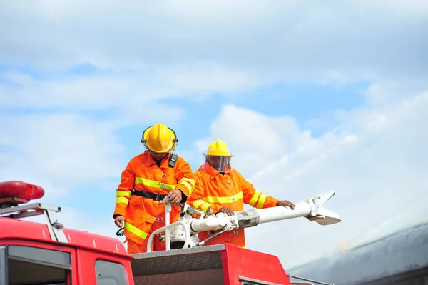 Skupina hasičů člověka se vstříkne rozstřikovat vodu k požáru acc — Stock fotografie
