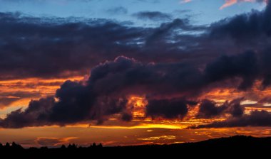 Kabarık bulutlar ve yanan ışıkları ile dramatik günbatımı gökyüzü