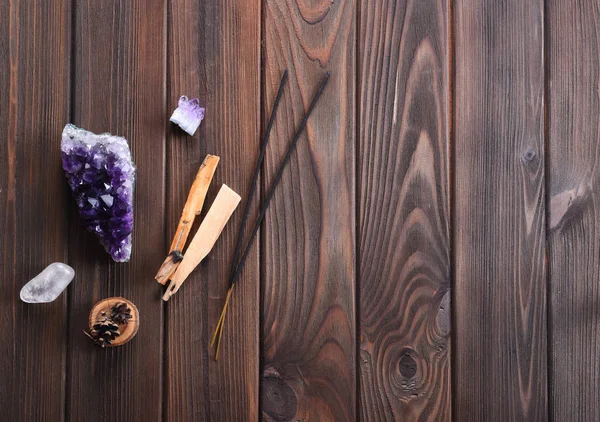 Şifa, meditasyon, gevşeme ve arıtma için kullanılan ezoterik nesneleri bileşimi. Ametist taşlar, palo santo ahşap, aromatik sopa üzerinde koyu arka plan. 