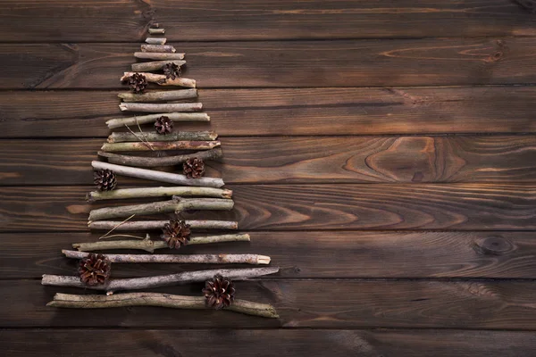 Árbol de Navidad hecho de ramas de madera seca con decoración de conos de pino sobre fondo de mesa de madera. Vista desde arriba. Año Nuevo y Navidad tarjeta de fondo . —  Fotos de Stock