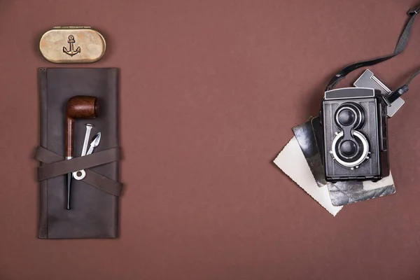 Sammansättningen av röka röret på ett brunt läderfodral, tobak tillbehör, gamla kamera och vintage fotografier. Ovanifrån. — Stockfoto