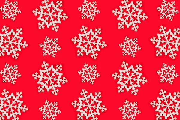 Modèle composé de flocons de neige blancs sur fond de fête rouge . — Photo