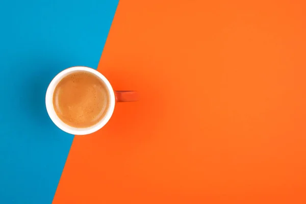 Φρέσκος καφές σε κεραμικό κύπελλο πάνω από πορτοκαλί και μπλε φόντο. Θέση για κείμενο. — Φωτογραφία Αρχείου