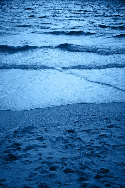 Achtergrond van de oceaan golf en zandstrand gekleurd in blauw. — Stockfoto