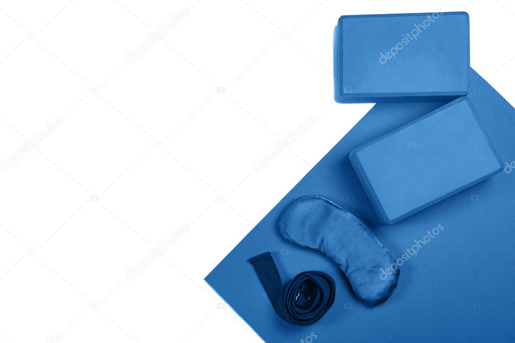 Composition of yoga, meditation or pilates accessories blue colored on white background with copy space. Top view.