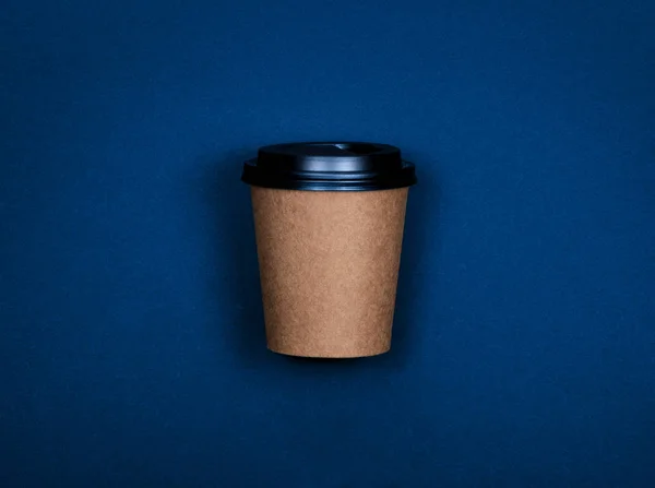 Taza de papel de artesanía marrón simple de café para ir sobre fondo de color azul con espacio de copia . — Foto de Stock