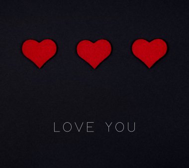 Siyah arka planda kırmızı kalplerden oluşan bayram kartı.