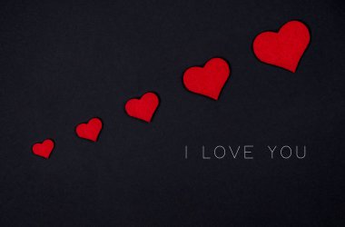 Siyah arka planda kırmızı kalplerden oluşan bayram kartı.