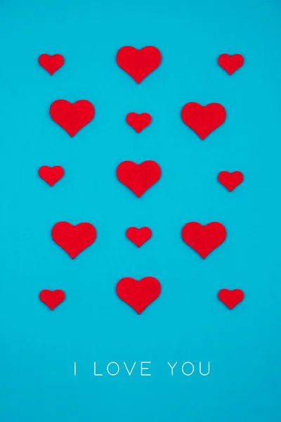 Greeting holiday card made of red hearts over blue background. — Stock Photo, Image