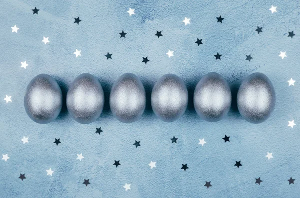 Prata colorido ovos de Páscoa e estrelas em fundo azul texturizado . — Fotografia de Stock