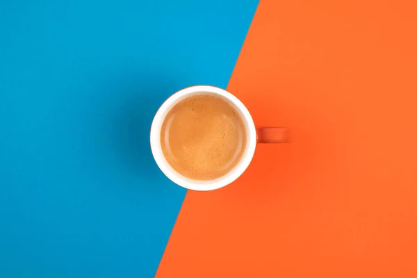 Café recién hecho en taza de cerámica sobre fondo naranja y azul. Lugar para el texto . —  Fotos de Stock