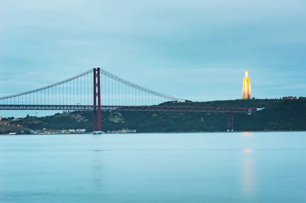 24 kwietnia most i Cristo Rei w Lizbonie o zmierzchu — Zdjęcie stockowe