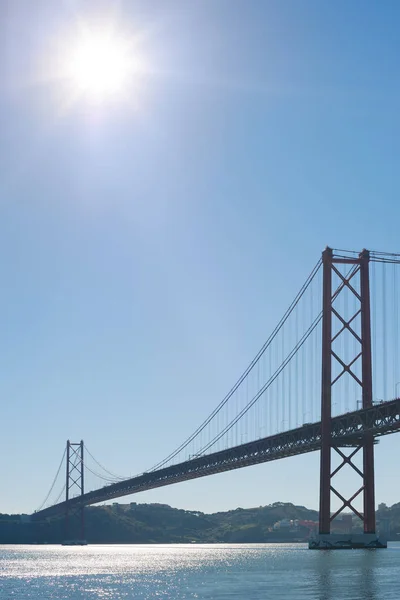 Lisbon 25 april suspension bridge againt blue sky and sun — Stock Photo, Image