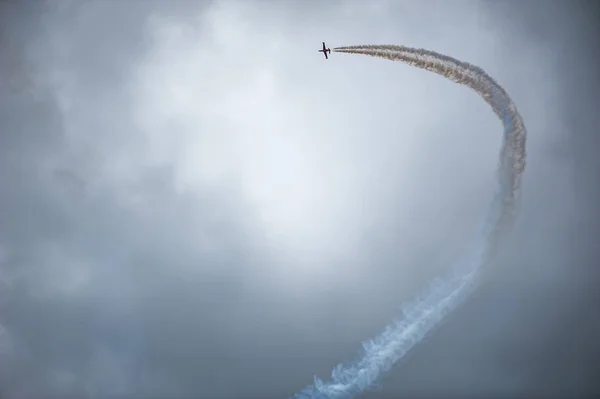 Jet airplane making a curve with white smoke against a dark sky — Stock Photo, Image