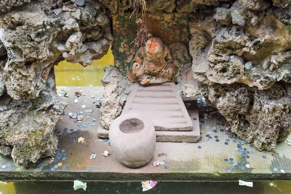 Buddha v kameni s mincí a bankovek kolem něj — Stock fotografie
