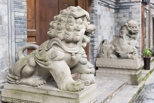 Két oroszlán kő szobrok előtt egy fából készült ajtó Kínában — Stock Fotó