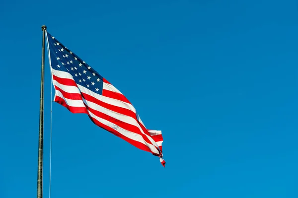 Schwebende amerikanische Flagge gegen blauen Himmel — Stockfoto