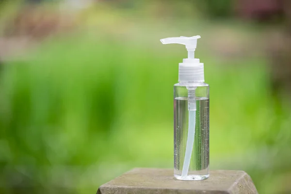 Hand sanitizer container against green vegetation — Stock Photo, Image