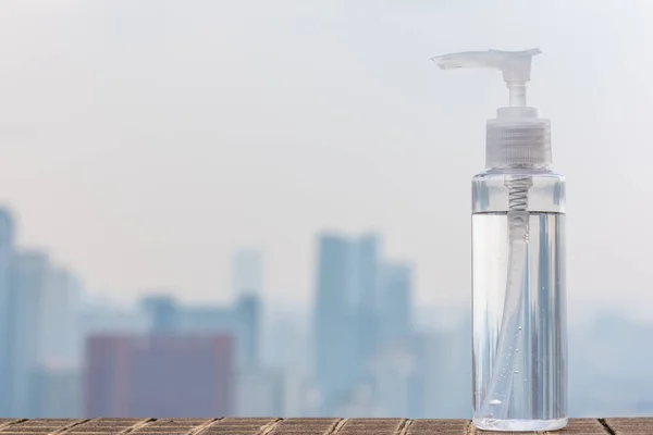 Hand sanitizer container against city skyline aerial view — Stock Photo, Image