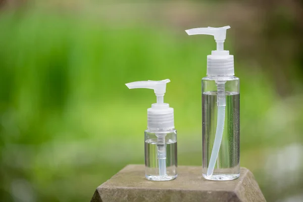 Two hand sanitizer containers against green vegetation — Stock Photo, Image