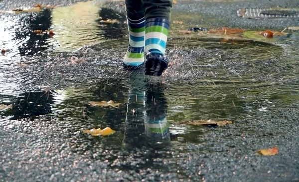Plastic boots running through the puddle in autumn Stock Obrázky