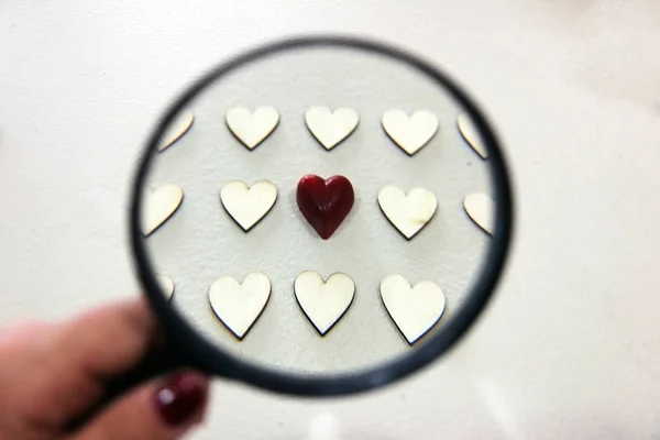 Red chocolate heart among wooden hearts seen through the lens — Stock Photo, Image