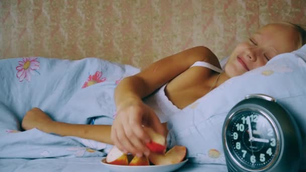 Fille dans le lit se réveille la nuit de la faim et manger des pommes — Video