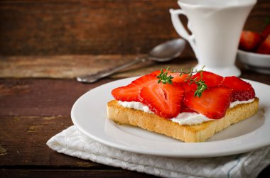 Krem peynir, çilek ve kekik ahşap masa üzerinde kızarmış ekmek
