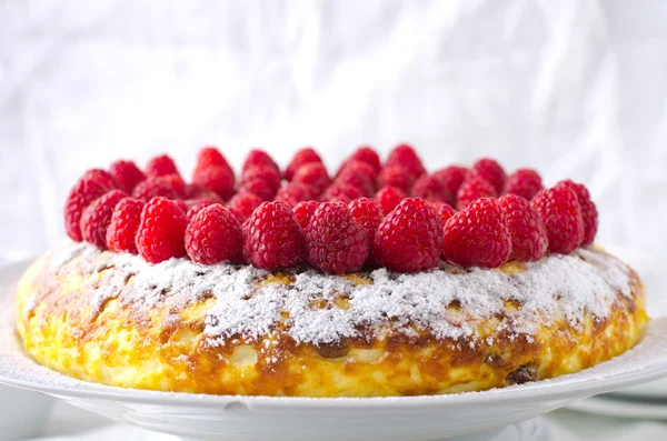 Bolo de queijo, souffle, mousse de creme, sobremesa de pudim com framboesas frescas e folhas de hortelã em um prato branco — Fotografia de Stock