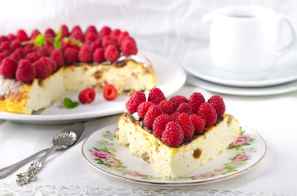 Torta di formaggio, soufflé, mousse alla panna, dolce budino con lamponi freschi e foglie di menta su un piatto bianco — Foto Stock