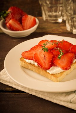 Krem peynir, çilek ve kekik ahşap masa üzerinde kızarmış ekmek