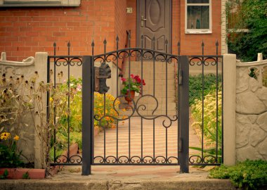 Kırmızı ev cephe demir çit, yeşil ağaçlar ve çiçekler