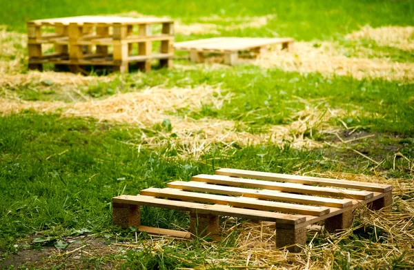 Empty wooden pallets on green grass — Stock Photo, Image