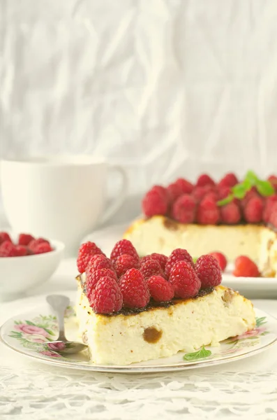 Torta di formaggio, soufflé, mousse alla panna, dolce budino con lamponi freschi e foglie di menta su un piatto bianco — Foto Stock