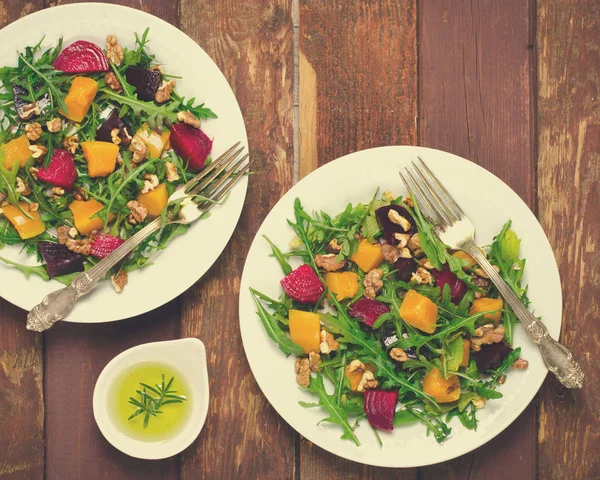 Herbstsalat mit Gemüse, Rucola, Walnüssen, Roter Bete und geröstetem Kürbis, Kürbis auf Holzgrund — Stockfoto
