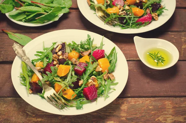 Ensalada de otoño con verduras, rúcula, nueces, remolacha y calabaza asada, calabaza sobre fondo de madera — Foto de Stock