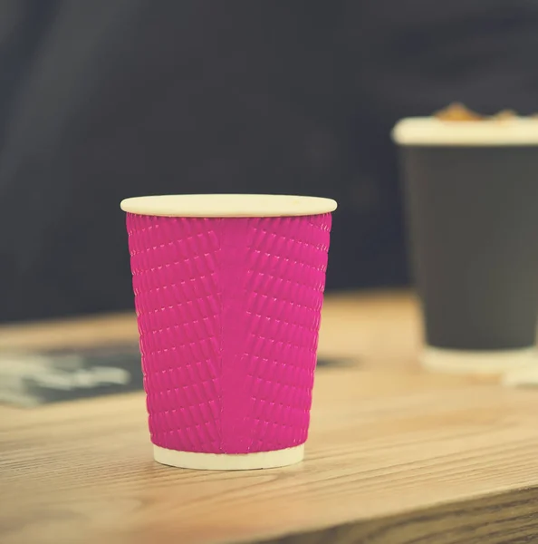 Tazze di caffè in carta artigianale nera e rosa in caffè su tavolo di legno. Stile di vita, concetto di caffetteria . — Foto Stock