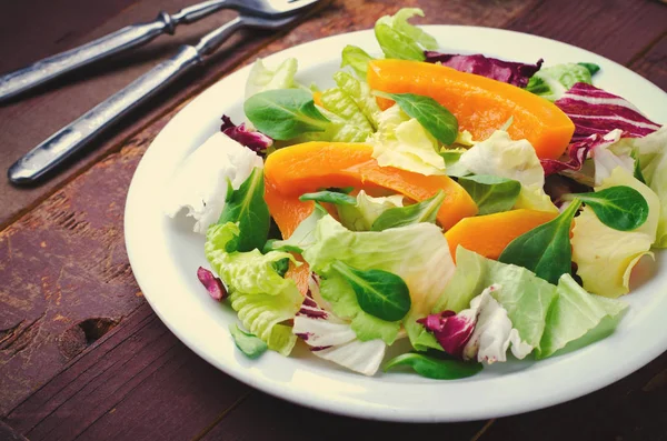 Salada de outono com verduras, rúcula, sementes de linho e abóbora assada, abóbora sobre fundo de madeira — Fotografia de Stock