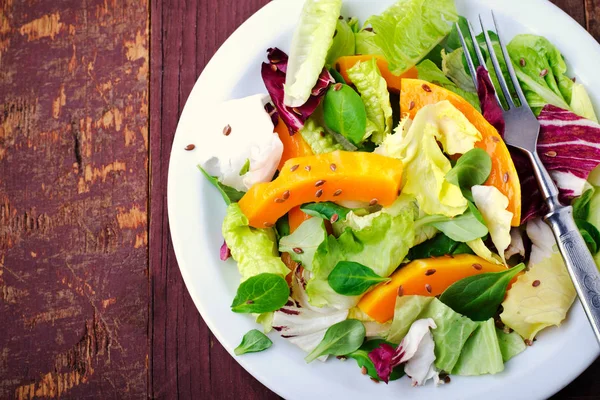 Herbstsalat mit Gemüse, Rucola, Leinsamen und geröstetem Kürbis, Kürbis auf Holzgrund — Stockfoto