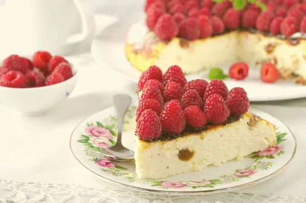 Torta di formaggio, soufflé, mousse alla panna, dolce budino con lamponi freschi e foglie di menta su un piatto bianco — Foto Stock